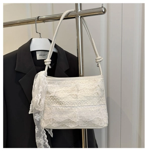 Détail du sac d'épaule en dentelle blanche avec volants étagés et décoration de nœud