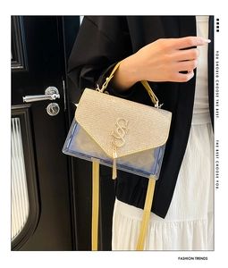 Close-up of vibrant blue PVC crossbody bag with gold glitter flap and metal tassel