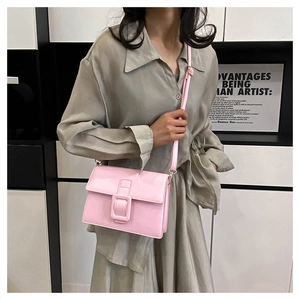 Pink rectangular crossbody bag with decorative buckle shown on model in a studio setting