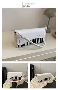Detail of white shoulder bag with piano key pattern and gold music note metal logo