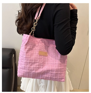 Detail of pink textured fabric tote bag with golden metal chain strap and leather patch