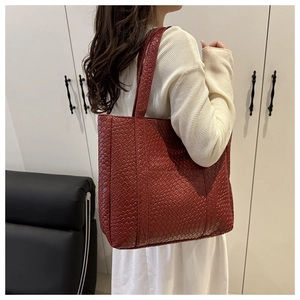 Detailed view of dark red woven leather tote bag texture with shoulder strap
