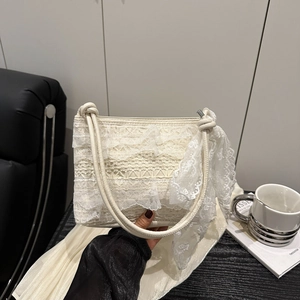 Sac bandoulière crème en dentelle avec nœud décoratif sur un bureau en bois vintage