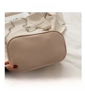 Close-up of beige leather pillow bag featuring silver chain strap and fashion text detail