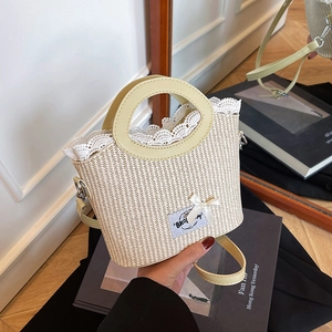 Chic beige straw bucket bag with delicate white lace trim and ribbon for summer