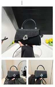 Detail of black sequined handbag featuring a silver heart-shaped metallic buckle clasp