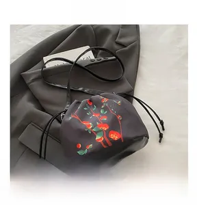 Detail of drawstring bucket bag with red fruit pattern on a gray blazer background