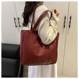 Detail of red woven texture on a large tote bag with a wide shoulder strap
