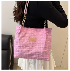 Close-up of pink quilted tote bag showing textured grid fabric and gold chain shoulder strap