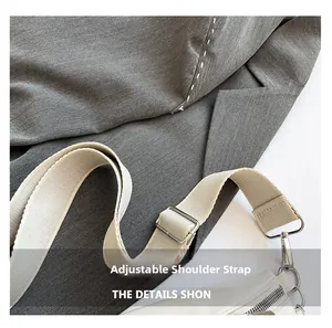 Detail of adjustable beige fabric strap and silver metal buckle on a saddle bag