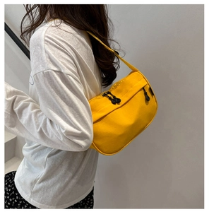 Model wearing a bright yellow canvas crescent shoulder bag with black zippers