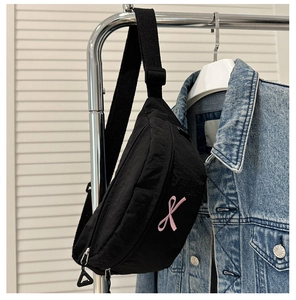 Détail du sac banane en nylon noir avec broderie nœud rose et bandoulière réglable