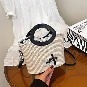 Summer woven straw handbag with white lace trim, black round handle and ribbon bow detail