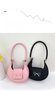 Dettaglio di borse a mezzaluna rosa e nere con fiocchi dorati e trama in pelle Saffiano