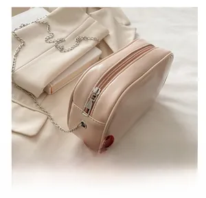 Detail showing the smooth silver zipper closure on a minimalist beige crossbody bag