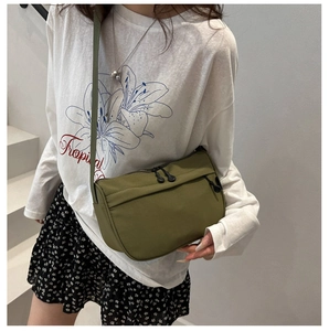 Army green nylon crossbody bag featuring dual metal zippers and front pocket on a model