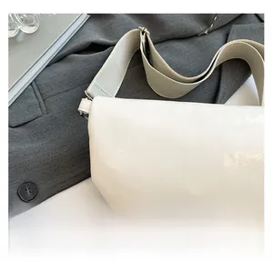 Side view of cream saddle bag with wide woven strap and fine leather texture details