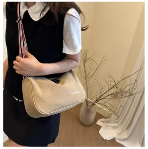 Détail du sac bandoulière kaki avec sangle tissée rayée et logo blanc de la marque