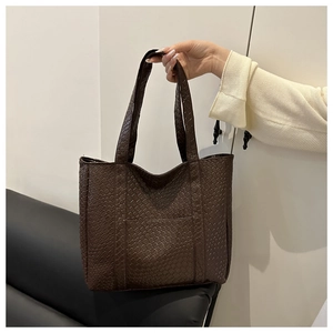 Detail of dark brown tote bag showing intricate woven texture and leather-like PU material