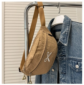 Détail du sac de poitrine en nylon marron avec broderie croisée et tirettes vertes