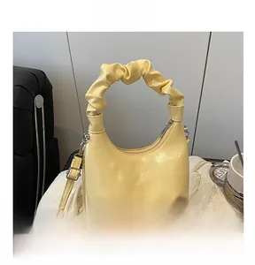 Detailed view of yellow ruched handbag handle with glossy finish and silver hardware