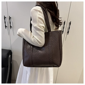 Macro shot of dark brown woven tote bag showing premium intrecciato texture and detail