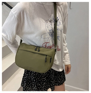 Close-up of army green nylon crossbody bag with multi-pockets and adjustable strap