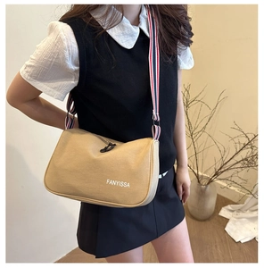 Détail du sac bandoulière en toile kaki avec sangle rayée et lettrage FANYISSA