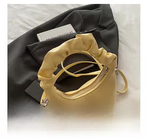 Detail of light yellow crescent bag with pleated handle and smooth metal zipper closure