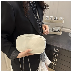 Close-up of cream PU leather vanity bag with silver chain strap worn with a black blazer