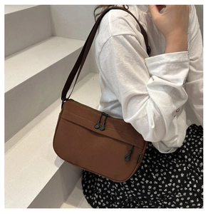 Detailed view of a brown canvas crossbody bag with multi-pocket design on stairs