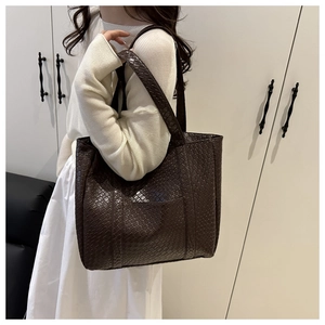 Detailed view of deep brown woven leather tote bag worn by model for casual style