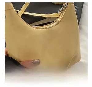 Close-up of light yellow crescent shoulder bag with pleated leather texture details