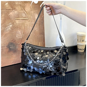 Close-up of black sequined shoulder bag with silver metal chain and leather handle strap