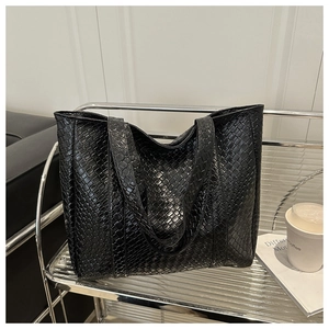 Macro detail of high-quality black woven texture on a large minimalist leather tote bag