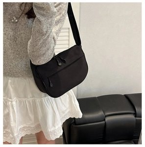 Detail of a black waterproof crossbody bag with smooth nylon texture and zip closure