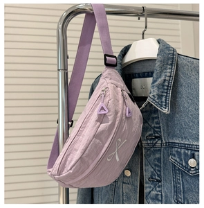 Détail du sac de poitrine en nylon lilas avec double fermeture éclair et broderie nœud