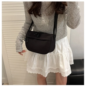 Model wearing a lightweight black nylon crossbody bag with adjustable strap and dual zippers