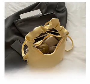 Detail view of the yellow pleated dumpling bag showing interior capacity with phone and wallet