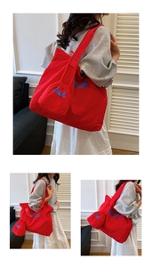 Detail of red canvas tote bag with blue Beach embroidery and matching drawstring pouch