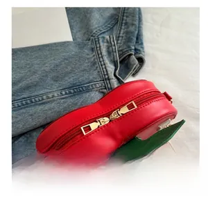 Top view detail of the red cherry bag featuring golden dual zippers and green leaf accents