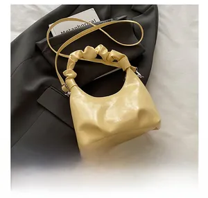 Detail of cream pleated handbag with silver logo, detachable strap, and soft PU leather texture