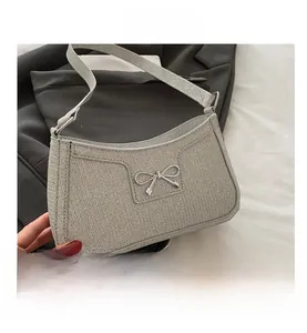 Detail of silver glitter underarm bag with a metallic bow buckle and shimmer texture