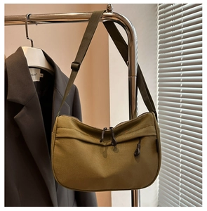 Close-up of olive green crescent canvas crossbody bag with dual zippers and woven strap