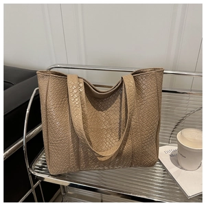 Detail of the woven texture and large interior of a tan faux leather tote shoulder bag