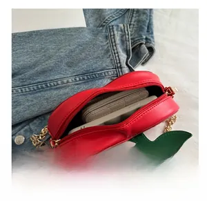 Detail view showing the interior capacity of a creative cherry-shaped red crossbody bag