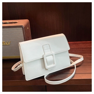 Close-up of white minimalist shoulder bag with a large buckle on a retro wooden table