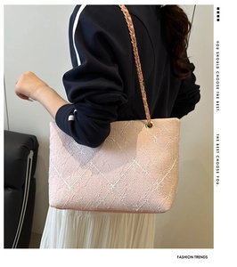 Detail of pink quilted tote bag featuring floral patterns and gold-tone chain strap