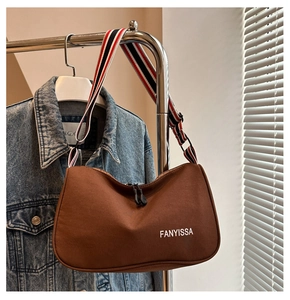 Détail du sac croissant avec large bandoulière rayée colorée et logo FANYISSA