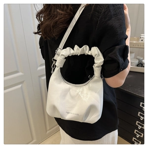 Close-up of a white pleated bucket bag with a glossy finish and adjustable strap